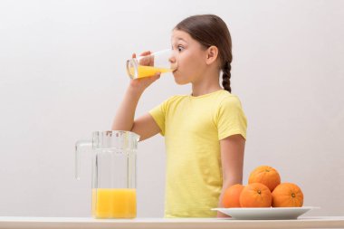 Güzel küçük kız portakal suyu içiyor. Sevinç kavramı bir
