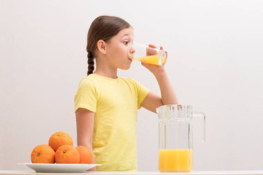 Güzel küçük kız portakal suyu içiyor. Sevinç kavramı bir
