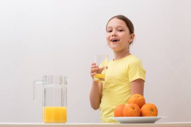 Güzel küçük kız portakal suyu içiyor. Sevinç kavramı bir