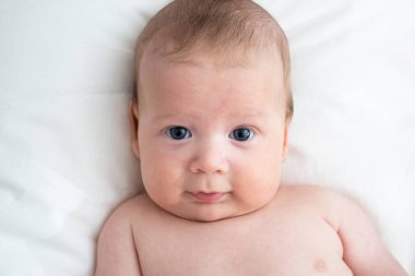 Beyaz bir battaniyenin üzerinde yatan mutlu bebek. Saflık ve j kavramı