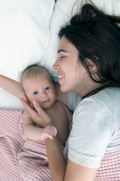 Beautiful brunette girl hugs and plays with baby. The concept of — Stock Photo, Image