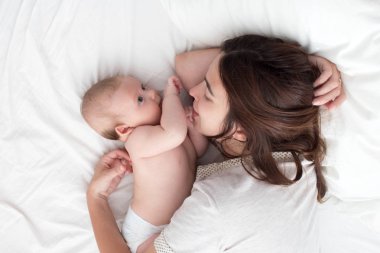Güzel esmer kız kucaklar ve bebek ile oynar. Kavramı
