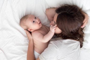 Güzel esmer kız kucaklar ve bebek ile oynar. Kavramı