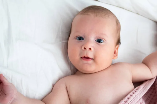 A meglepett baba fekszik egy fehér takaró. Az Inter- — Stock Fotó