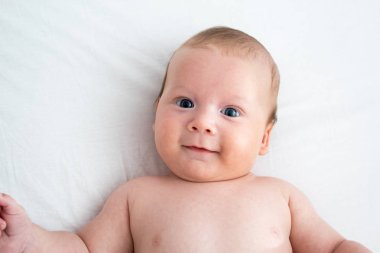 Beyaz bir battaniyenin üzerinde yatan mutlu bebek. Saflık ve j kavramı