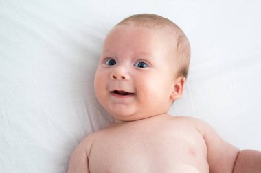 Beyaz bir battaniyenin üzerinde yatan mutlu bebek. Saflık ve j kavramı