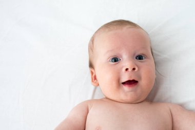 Beyaz bir battaniyenin üzerinde yatan mutlu bebek. Saflık ve j kavramı