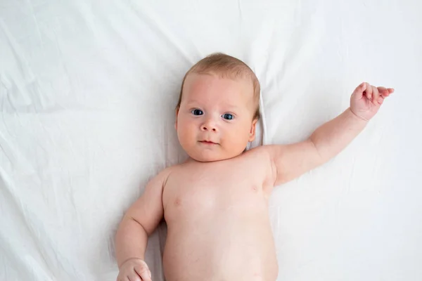 Boldog baba feküdt egy fehér takaró. A fogalom a tisztaság és a j — Stock Fotó