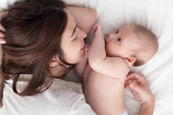 Vacker brunett flicka kramar och leker med baby. Begreppet — Stockfoto