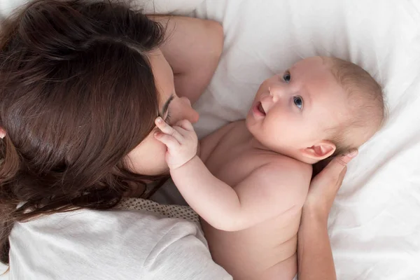 Beautiful brunette girl hugs and plays with baby. The concept of — Stock Photo, Image