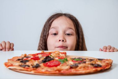 Küçük kız pizzaya bakıyor. Çocuk pizza buldu