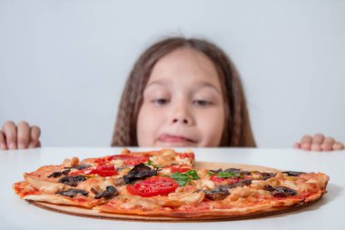 Küçük kız pizzaya bakıyor. Çocuk pizza buldu