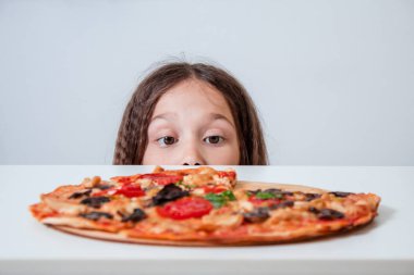 Küçük kız pizzaya bakıyor. Çocuk pizza buldu