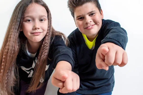 A little girl and a boy point at the camera