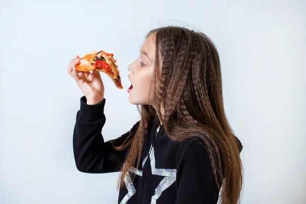 Niña comiendo pizza. Bebé pone pizza en su boca Imagen de archivo