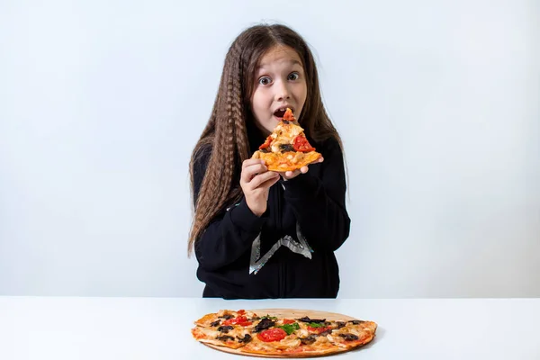 Niña comiendo pizza. Bebé pone pizza en su boca Imagen de archivo