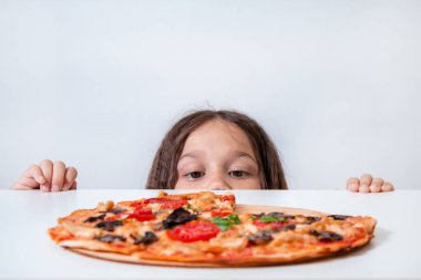 Küçük kız pizzaya bakıyor. Çocuk pizza buldu