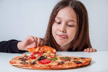 Küçük kız bir dilim pizza alıyor. Çocuk pizza yiyor.