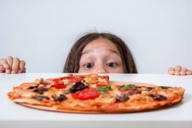 Küçük kız pizzaya bakıyor. Çocuk pizza buldu