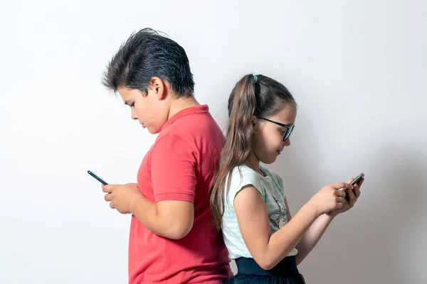 Ένα μικρό κορίτσι και ένα αγόρι που κοιτάνε έξυπνα τηλέφωνα. Τα παιδιά είναι πα — Φωτογραφία Αρχείου