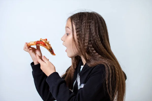 Niña comiendo pizza. Bebé pone pizza en su boca Imagen de stock