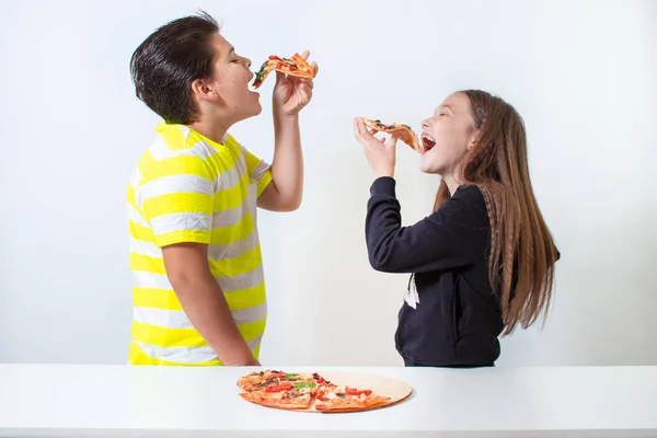 Niño y niña comiendo pizza. Los niños almorzan. Imagen de stock