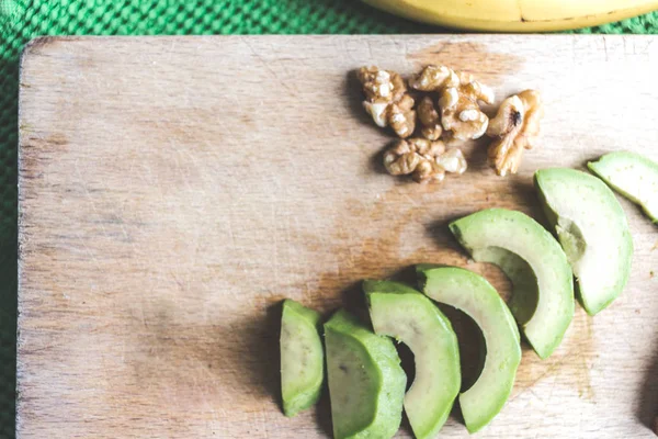 Fresh avocado slices and nuts on a board