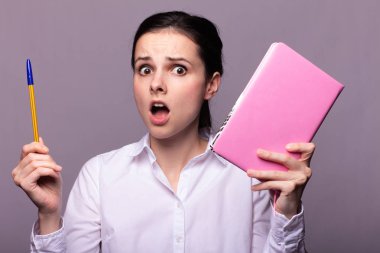 beyaz gömlekli kız elinde pembe bir defter tutar