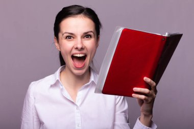 beyaz gömlekli kız elinde kırmızı bir defter tutar