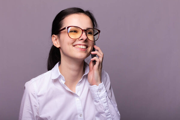 beautiful girl in a white shirt and glasses for vision communicates on the phone