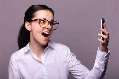 Beyaz gömlekli ve gözlüklü güzel kız telefonla konuşuyor.