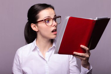 beyaz gömlek ve gözlük kız elinde kırmızı bir defter tutar