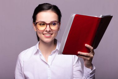 beyaz gömlek ve gözlük kız elinde kırmızı bir defter tutar