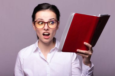 beyaz gömlek ve gözlük kız elinde kırmızı bir defter tutar
