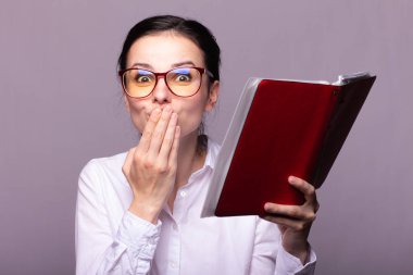 beyaz gömlek ve gözlük kız elinde kırmızı bir defter tutar