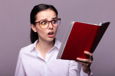 beyaz gömlek ve gözlük kız elinde kırmızı bir defter tutar