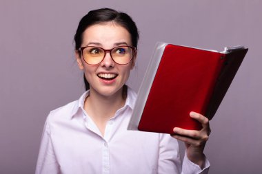 beyaz gömlek ve gözlük kız elinde kırmızı bir defter tutar