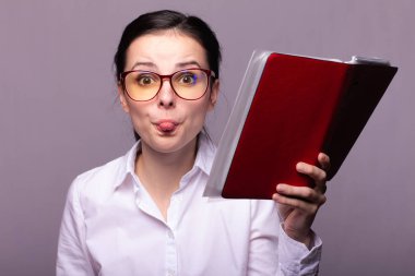 beyaz gömlek ve gözlük kız elinde kırmızı bir defter tutar