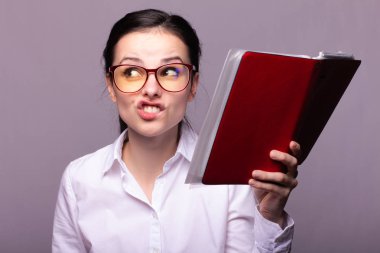 beyaz gömlek ve gözlük kız elinde kırmızı bir defter tutar