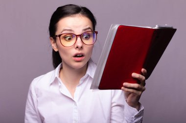 beyaz gömlek ve gözlük kız elinde kırmızı bir defter tutar