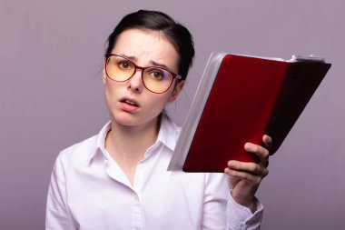 beyaz gömlek ve gözlük kız elinde kırmızı bir defter tutar