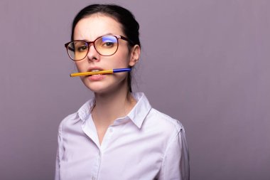 beyaz gömlek ve gözlük kız dişleri bir kalem tutar