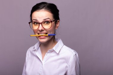 beyaz gömlek ve gözlük kız ağzıyla bir kalem tutar