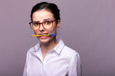 beyaz gömlek ve gözlük kız ağzıyla bir kalem tutar