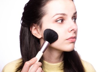 Çekici kız makyaj yapıyor, makyaj fırçası yapıyor.