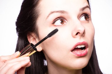 Güzel genç kız kirpiklerini boyuyor.