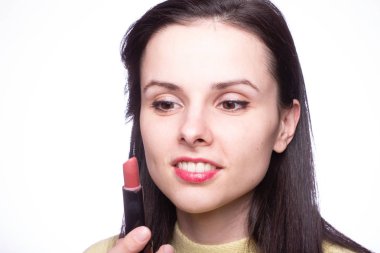 Güzel genç bir kadın rujla dudaklarını boyuyor.