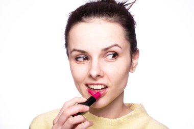Güzel genç bir kadın rujla dudaklarını boyuyor.
