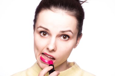 Güzel genç bir kadın rujla dudaklarını boyuyor.