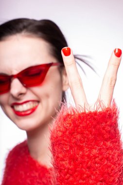 Kırmızı güneş gözlüklü genç kadın, kırmızı ruj, kırmızı kazak.